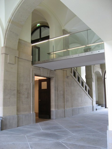 Das Foto zeigt das Foyer der Kunstsammlungen am Theaterplatz mit einem der zwei originalen Treppenaufgänge; zentral ist die Anfang der 2000er Jahre eingebaute gläserne Verbindungsbrücke zwischen West- und Ostflügel des Gebäudes.
