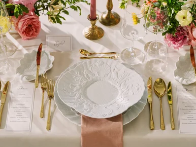 Tisch- und Tafelkultur bei MEISSEN Detailaufnahme einer festlich gedeckten Tafel mit weißem Meißener Porzellan und goldfarbenem Besteck, rings herum Blumen