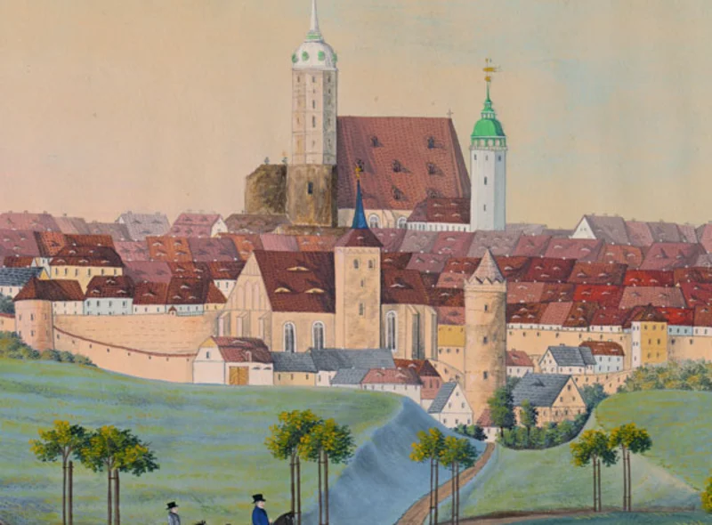 Türme, Dächer und die Mauer der Stadt Bautzen, davor grüne Wiesen und Wege, auf denen paarweise Personen zu sehen sind