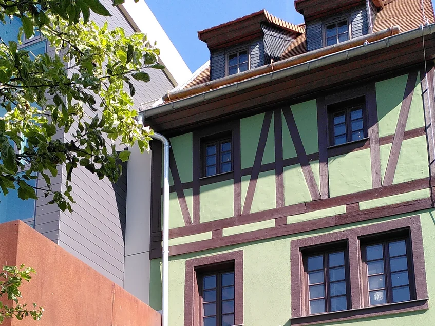 Das Karl-May-Haus in Hohenstein-Ernstthal Ein grünes Fachwerkhaus neben einem modernen Neubau