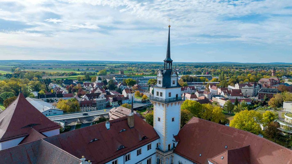 Das Bild zeigt eine mithilfe einer Flugdrohne fotografierte Panoramaansicht, mit Schloss Hartenfels einschließlich Hausmannsturm im Vordergrund.