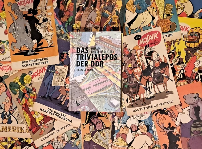 MOSAIK-Comics im Hintergrund, darüber mittig das Buch „Das Trivialepos der DDR. Mosaik und seine Quellen“ von Thomas Kramer
