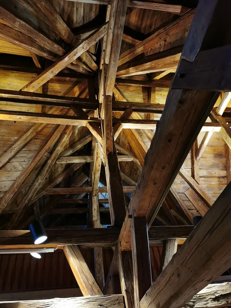 Deckenkonstruktion des Bürgersaals im Wasserschloss Klaffenbach Das Foto zeigt eine spitz nach oben zulaufende Deckenkonstruktion aus mächtigen alten Holzbalken.