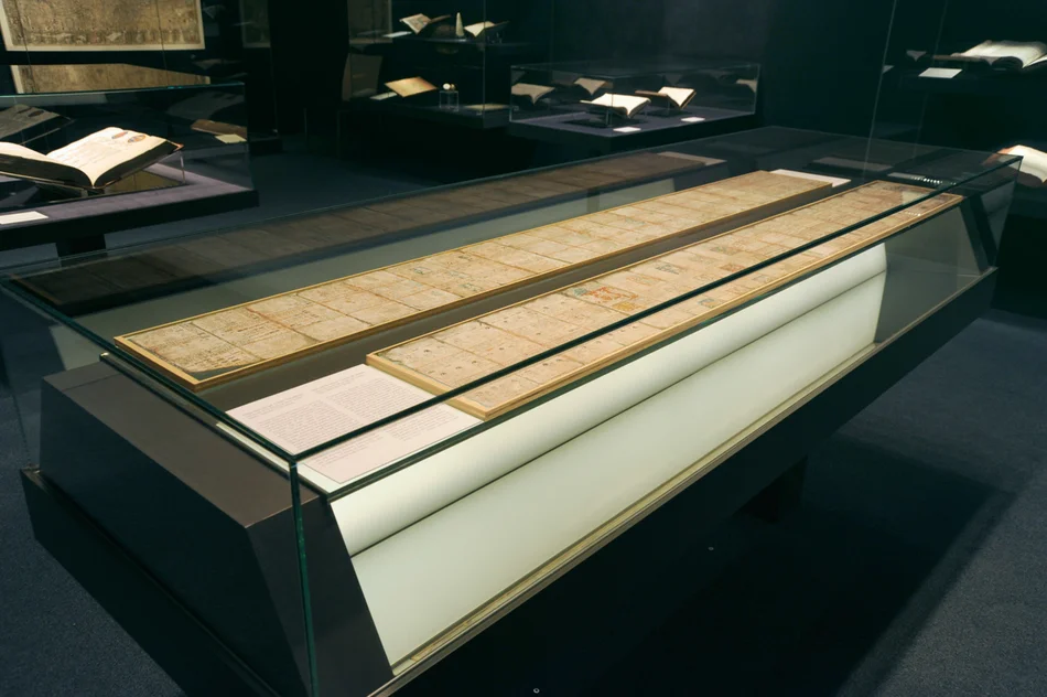 Zu sehen ist die große Flachvitrine in der Schatzkammer, in der die Maya-Handschrift ausgestellt wird. Die Aufnahme ist leicht schräg von oben aufgenommen, so dass erkennbar ist, dass die Handschrift in zwei Teilen ausgestellt wird und recht lange ist (insgesamt 3,56 Meter).