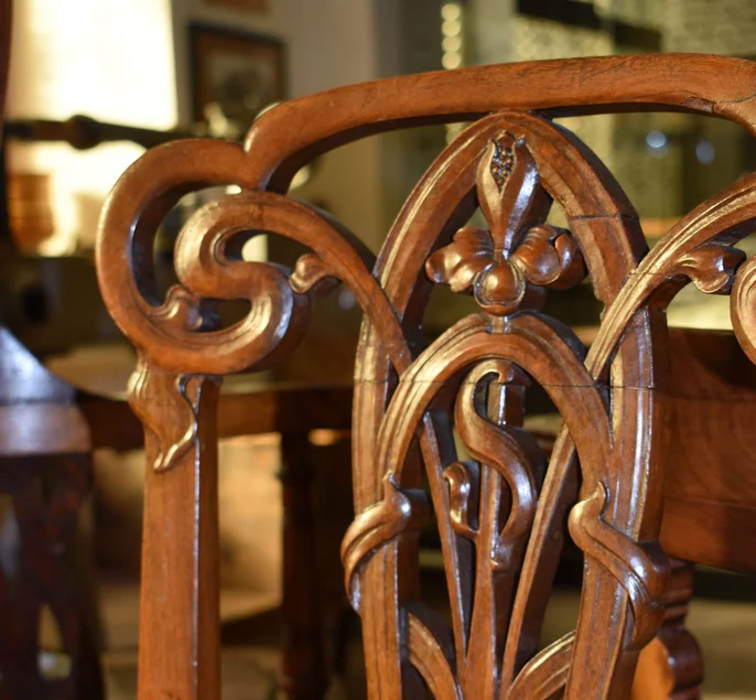 Das Foto zeigt die künstlerisch gestaltete, aus einem Geflecht geschwungener hölzerner Bänder bestehende Rückenlehne eines Stuhles.