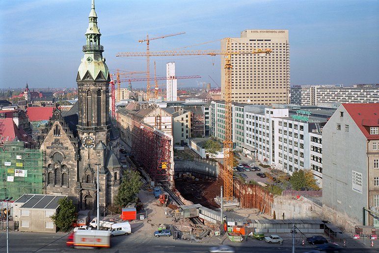 Die aus großer Höhe gemachte Aufnahme zeigt alte Bausubstanz und große Wohnblocks aus der DDR-Zeit, dazwischen eine Unzahl von Kränen