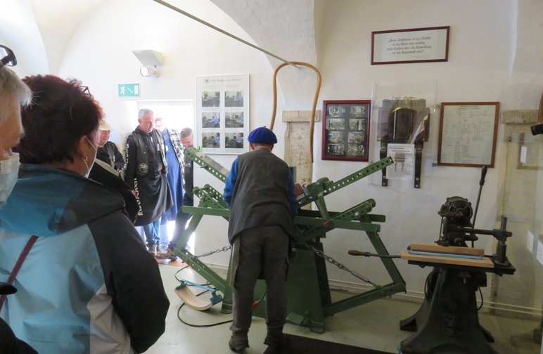 Besucherinnen und Besucher verfolgen die Vorführung eines Handwerkers im Holzbiegen an historischer Maschine