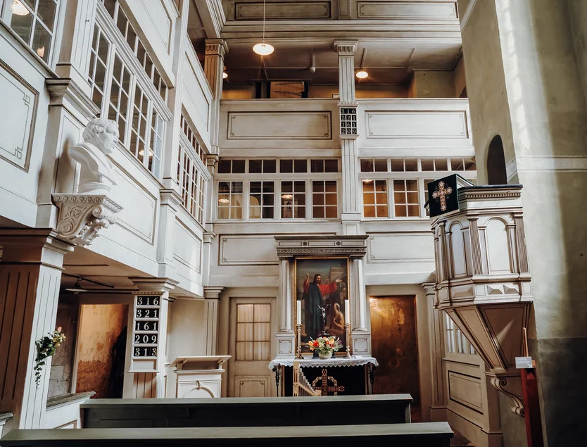 Schlosskapelle Colditz Blick ins Innere einer schnörkellosen Kapelle mit weißen Wandvertäfelungen und drei Emporen. Einziger farbiger Blickfang ist das Altargemälde.