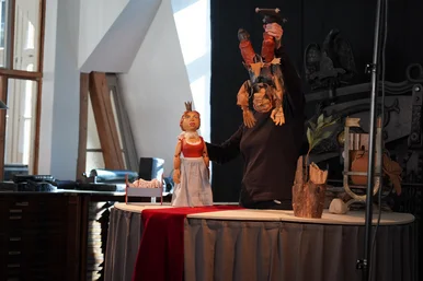 Eine vor schwarzem Vorhang stehende schwarz gekleidete Person führt zwei Handpuppen.