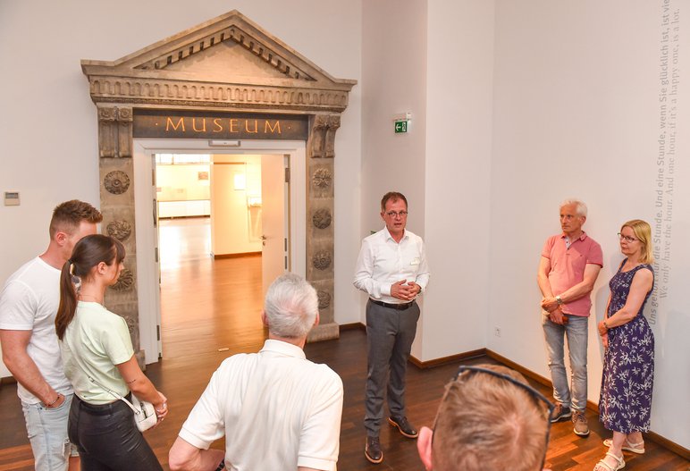 Das Foto zeigt eine Besuchergruppe mit Guide im Eingangsbereich zur Dauerausstellung des Deutschen Uhrenmuseums Glashütte.
