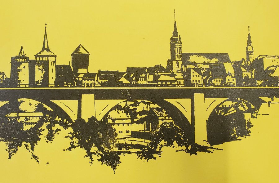 Einfarbiger schwarzer Druck auf gelbem Material, auf dem eine Ansicht der Bautzener Altstadt aus Richtung der Friedensbrücke erkennbar ist