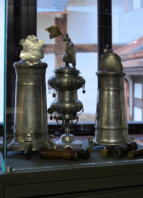 Vitrine mit zwei historischen Zinn-Krügen und einem weiteren dekorativen Zinn-Objekt