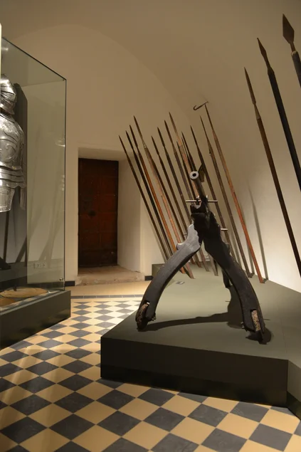 Ausstellungsraum mit einer Ritterrüstung sowie historischen Lanzen und anderen Waffen