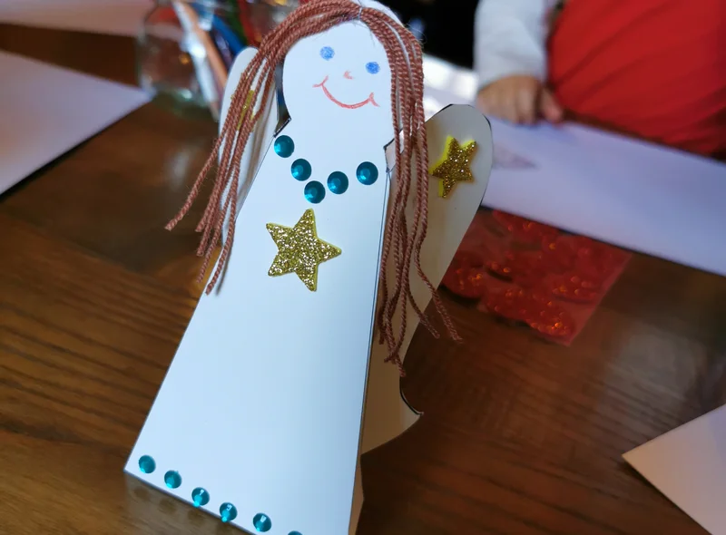 Selbst gebastelter Papier-Engel mit Wollhaaren und aufgemaltem Gesicht