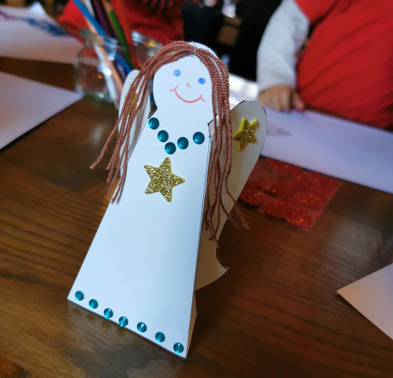 Selbst gebastelter Papier-Engel mit Wollhaaren und aufgemaltem Gesicht