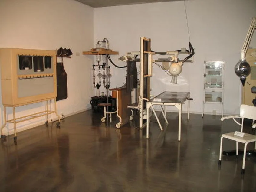 In einem klinisch anmutenden Raum stehen diverse historische medizinische Geräte.