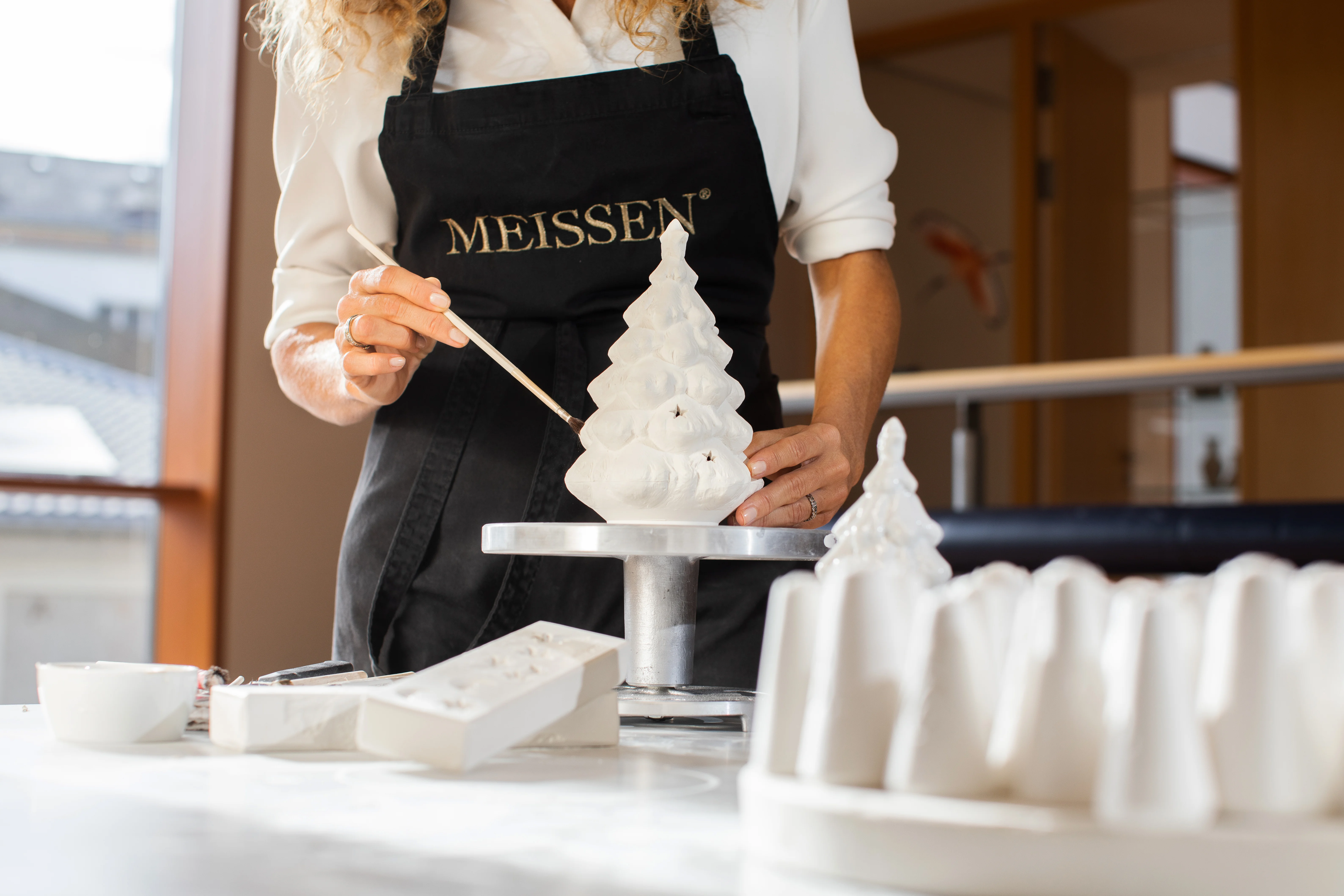 Im Winter-Workshop bei MEISSEN bearbeitet eine Teilnehmerin mit feinem Pinsel eine Porzellanfigur – konzentriert und kreativ.
