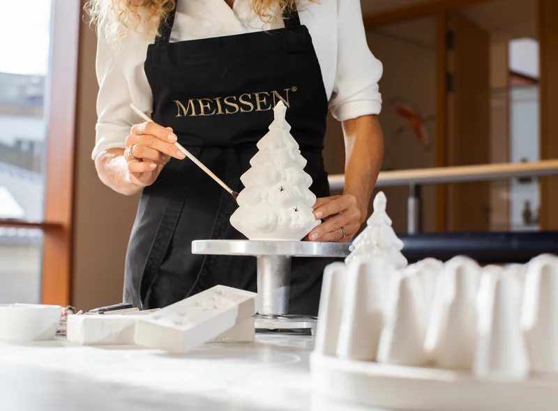 Im Winter-Workshop bei MEISSEN bearbeitet eine Teilnehmerin mit feinem Pinsel eine Porzellanfigur – konzentriert und kreativ.