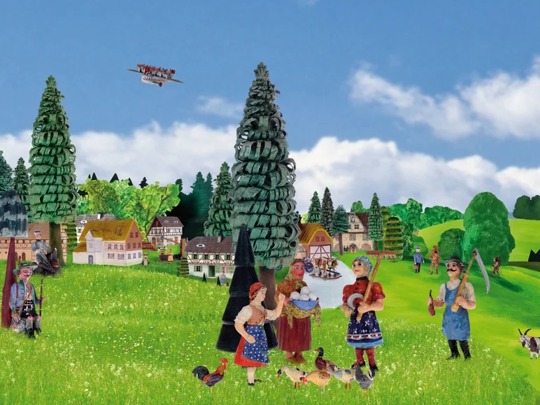 Das Bild zeigt eine bäuerliche Landschaft mit Figuren aus der Sammlung der Manufaktur der Träume: fünf historisch gekleidete menschliche Figuren im Vordergrund, auf einer hügeligen Wiese stehend, mehrere Fachwerkhäuser sowie ein Wald im Hintergrund.