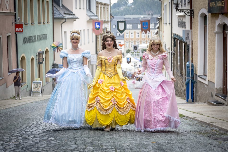Foto dreier als Prinzessinnen verkleideter junger Frauen in historischer Kopfsteinpflaster-Gasse
