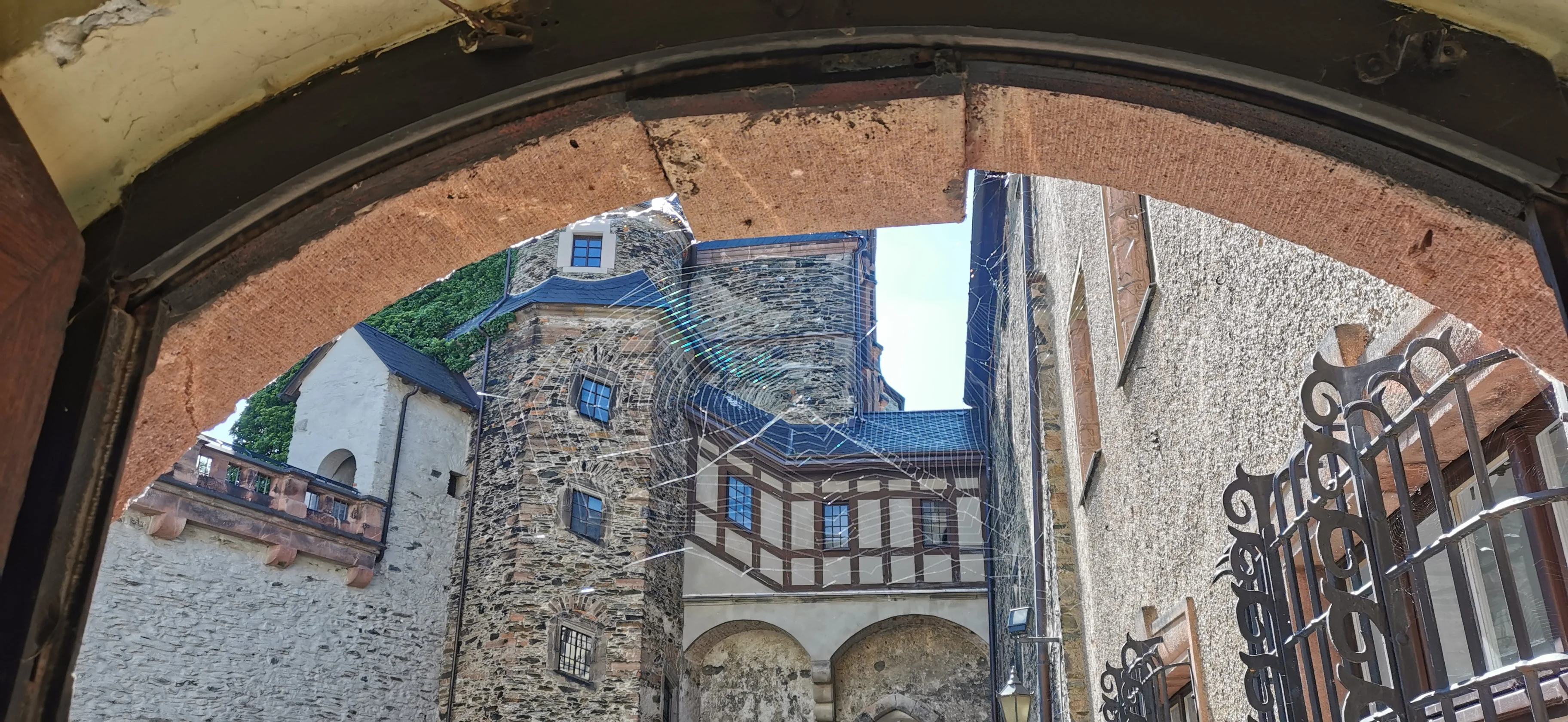 Burg Mylau, Hofansicht Blick durch einen steinernen Torbogen in den Innenhof einer mittelalterlichen Burg mit Fachwerk- und Naturstein-Elementen
