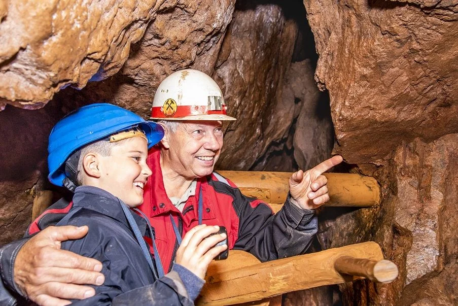 Bergbau erleben für Groß und Klein Ein Bergwerksführer zeigt einem Jungen einen Teil des Besucherbergwerks.