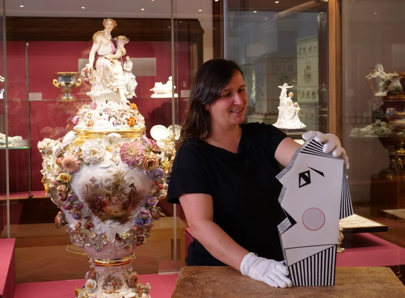 Eine Kuratorin erläutert im Museum der Meissen Porzellan-Stiftung ein opulent dekoriertes Porzellanobjekt.