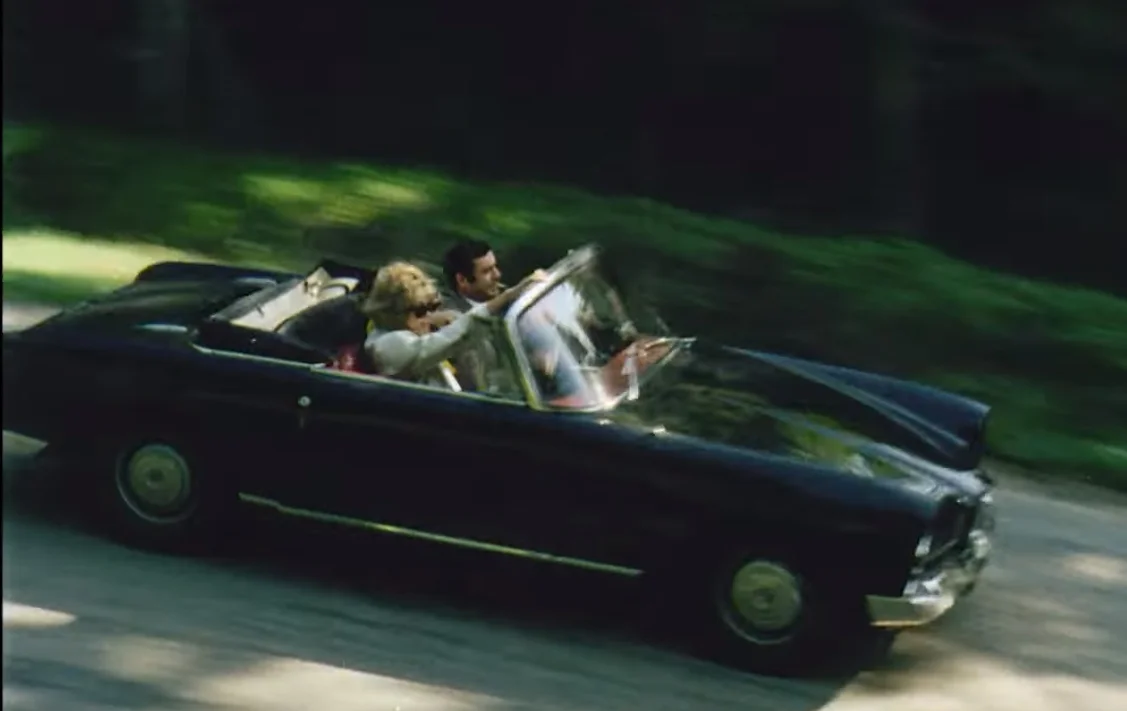 Luftaufnahme eines Mannes und einer Frau in einem fahrenden Cabriolet im Stil der 1960er Jahre