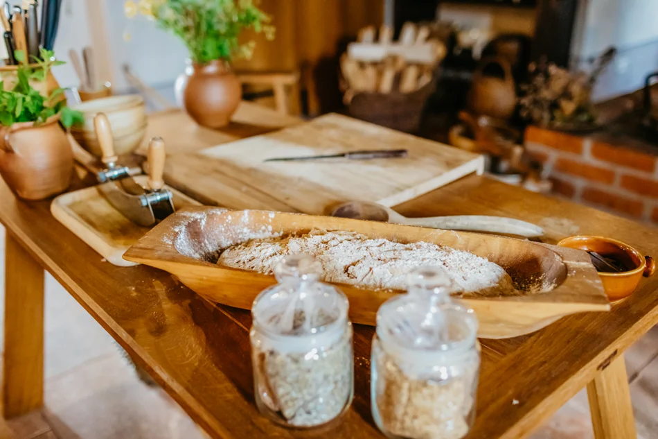Verschiedene Getreidekörner und ein fertiger Brotteigling liegen fürs Backen bereit.