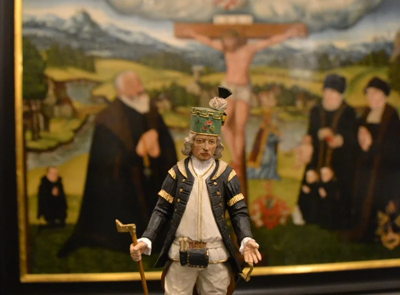 Das Foto zeigt den geschnitzten Paul-Schneider-Bergmann vor einem Lucas-Cranach-Gemälde im Erzgebirgsmuseum.