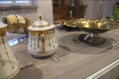 Blick in die Ausstellung Detailaufnahme einer Vitrine mit Porzellanobjekten und verzierten Metalltellern