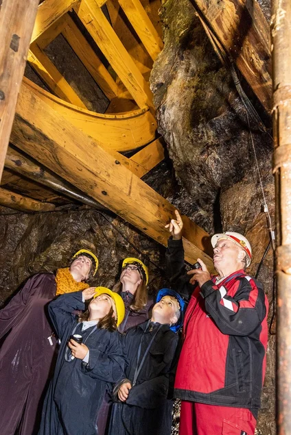 Die Ehrenfriedersdorfer Radpumpe Ein Bergwerksführer zeigt zwei Frauen und zwei Kindern das große hölzerne Rad der Radpumpe im Besucherbergwerk.