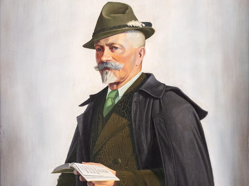 Anton-Günther-Portrait von Erwin Hilsky (Ausschnitt) Älterer Mann mit Spitzbart, Jägerhut und Anzug, in der linken Hand ein aufgeschlagenes Buch haltend