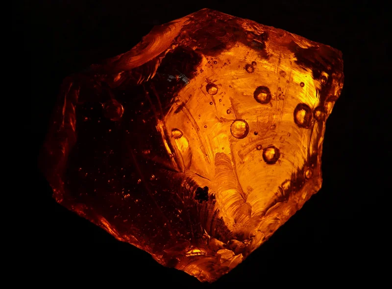 Rotgold schimmernder Bernstein vor dunklem Hintergrund
