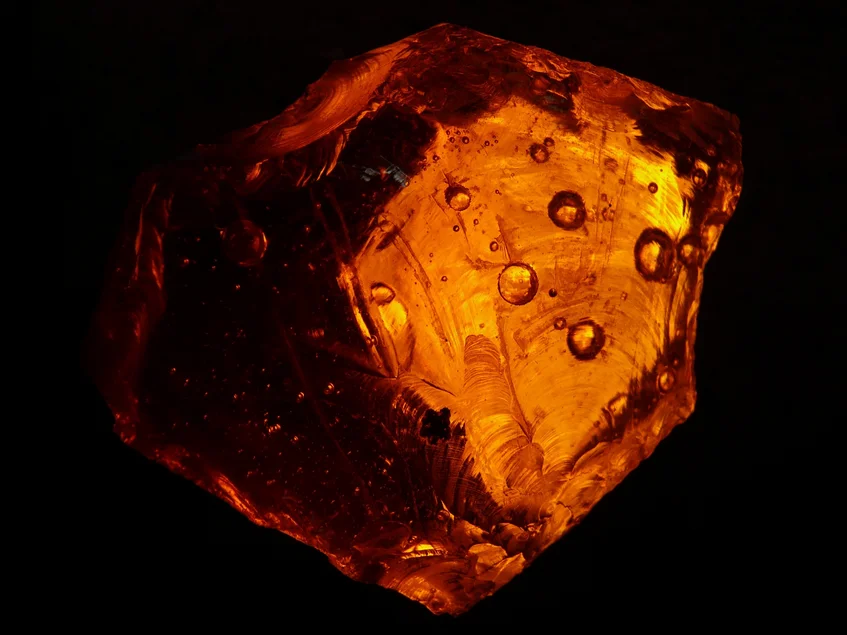 Rotgold schimmernder Bernstein vor dunklem Hintergrund