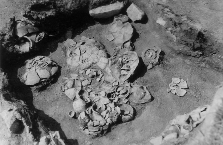 Schwarzweißfoto einer archäologischen Grabung, auf dem Tonscherben in einem quadratischen Feld zu sehen sind