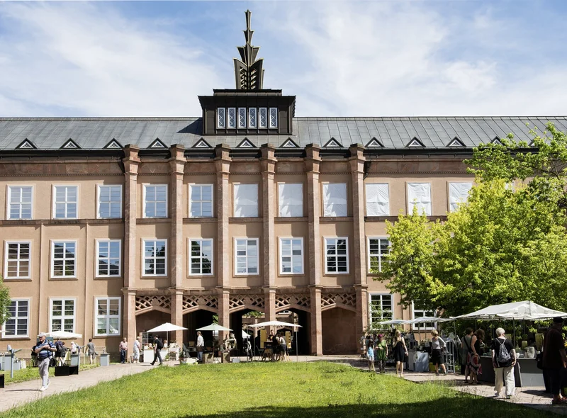Grassimuseum von außen mit Dachbekrönung und begrünten Höfen, in denen Verkaufsstände mit Keramik stehen