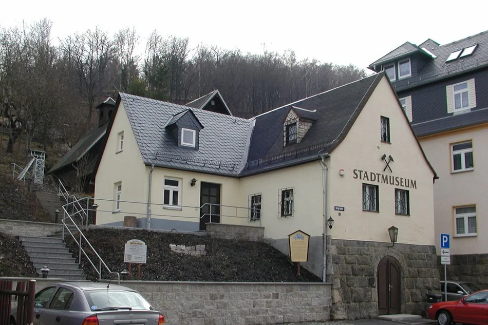 Museumsgebäude Außenansicht eines an einem Hang gebauten Gebäude-Ensembles mit Spitzdächern, welche mit schwarzem Schiefer gedeckt sind. An der Fassade des Gebäudes im Vordergrund steht das Wort Stadtmuseum.