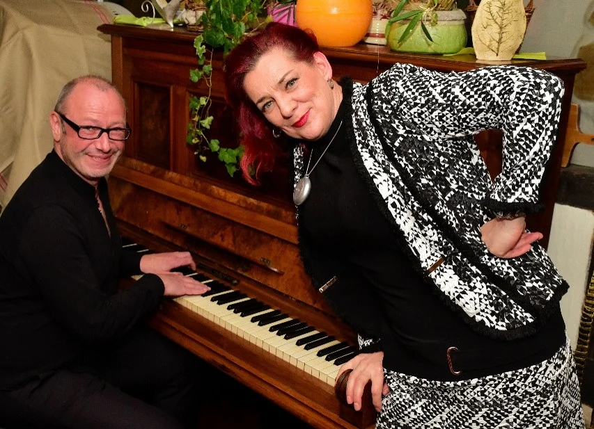 Jens Pflug und Ines Agnes Krautwurst Jens Pflug sitzt am Klavier, neben ihm steht die Sängerin Ines Agnes Krautwurst, beide lächeln in die Kamera.