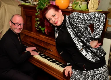 Jens Pflug und Ines Agnes Krautwurst Jens Pflug sitzt am Klavier, neben ihm steht die Sängerin Ines Agnes Krautwurst, beide lächeln in die Kamera.