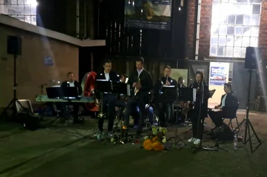 Ein Ensemble junger Jazzmusikerinnen und -musiker geben in einem historischen Lokschuppen ein Konzert.