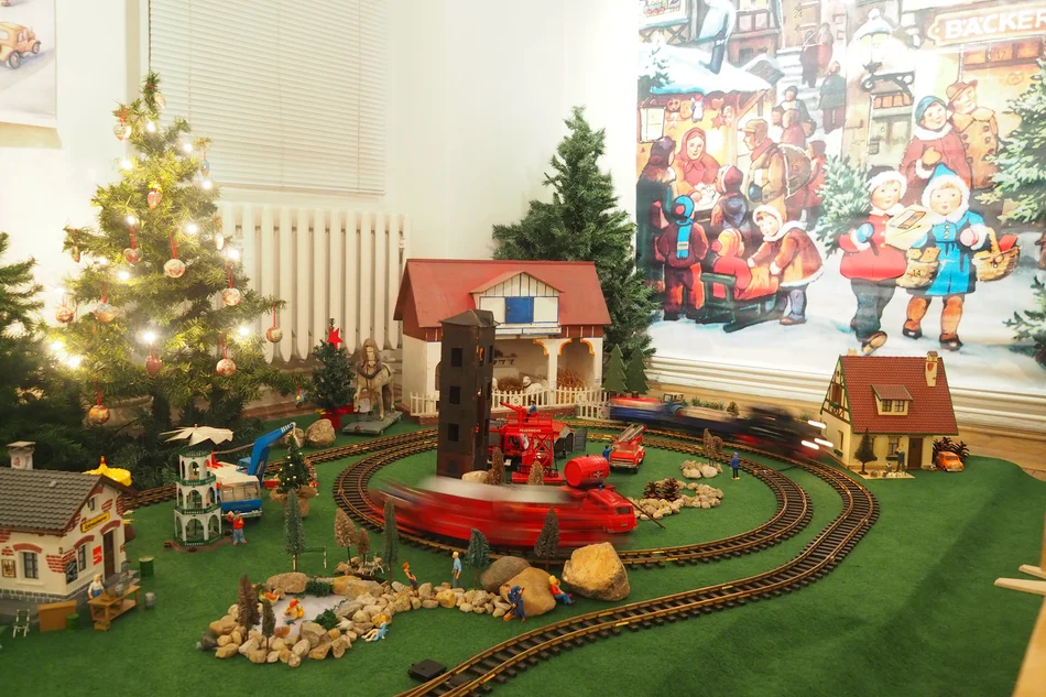 Eine Gartenbahn mit Eisenbahn in einer Miniaturlandschaft und Tannenbäumen in der Weihnachtsausstellung in Glauchau