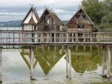 Rekonstruierte Pfahlbauten in Unteruhldingen am Bodensee In einem See stehen auf vielen Pfählen errichtet vier Holzhausrekonstruktionen.