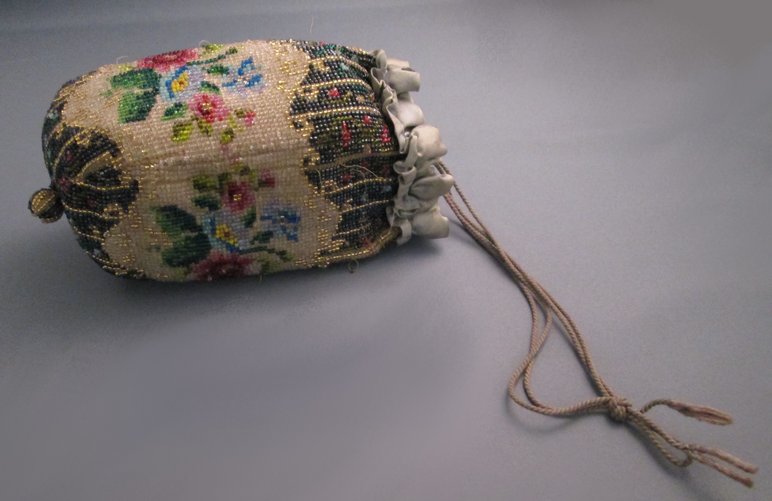 Ein mit bunten Glasperlen in floralen Motiven besticktes Handtäschchen mit leinenfarbener Kordel