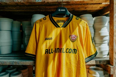 Ein gelbes Dynamo-Dresden-Trikot mit Zwiebelmuster-Relief zwischen weißen Porzellanformen – sportlich und überraschend.