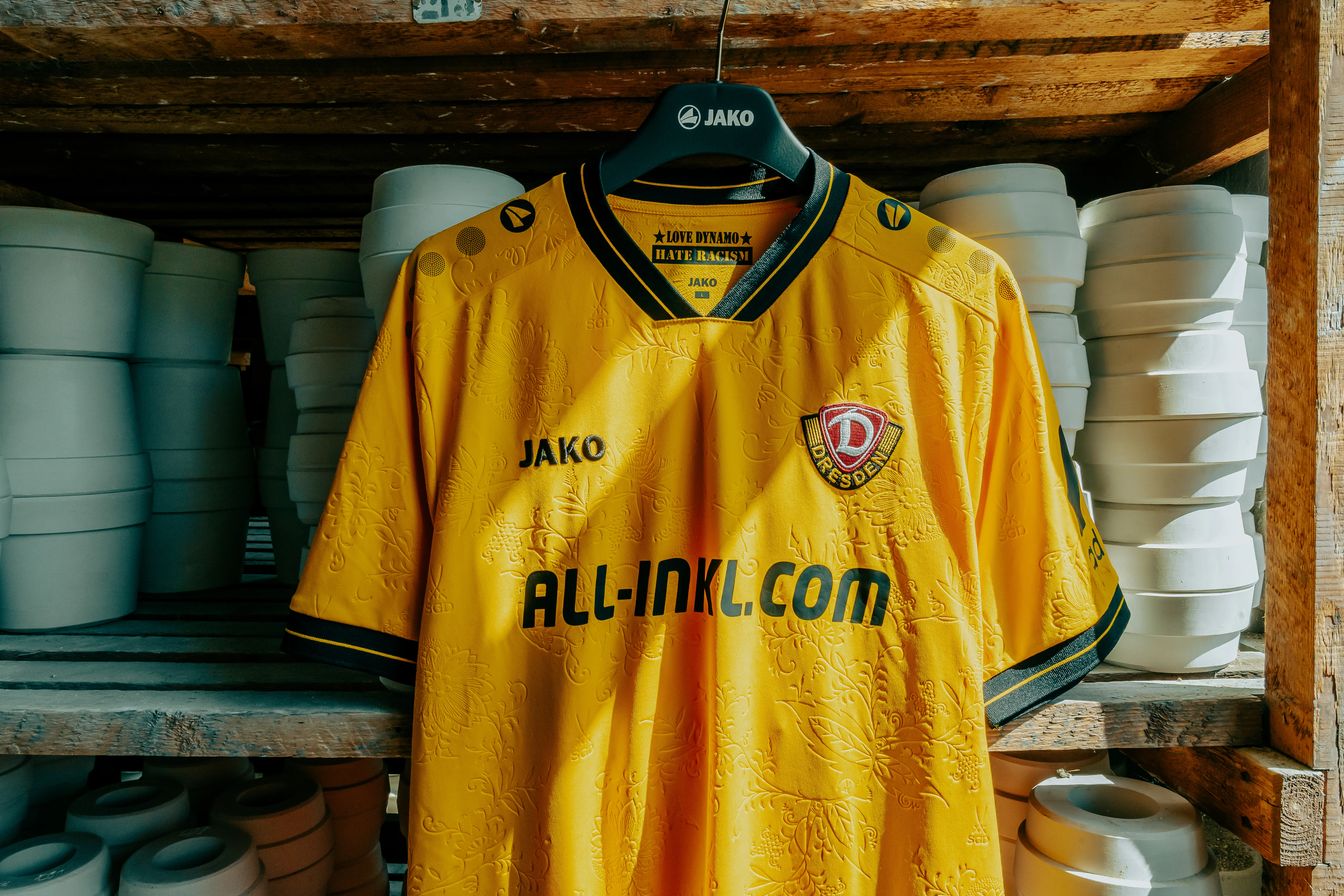 ManufakTOUR − auf den Spuren des Trikots Ein gelbes Dynamo-Dresden-Trikot mit Zwiebelmuster-Relief zwischen weißen Porzellanformen – sportlich und überraschend.