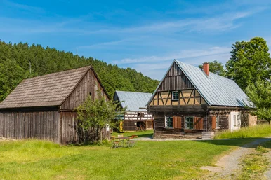 Historisches Bauernhof-Ensemble, bestehend aus zwei Fachwerkhäusern und einer Holzscheune, davor ein Tisch mit Stühlen