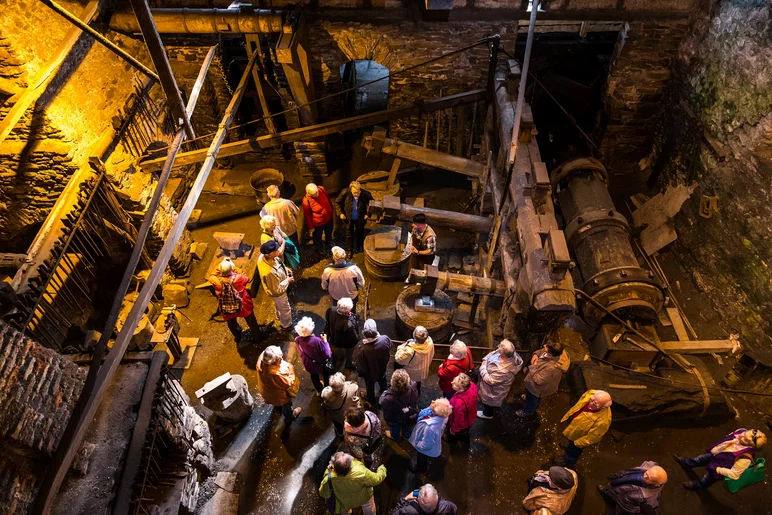Diese Vogelperspektive zeigt eine große Personengruppe bei einer Führung durch das Hammerwerk des historischen Frohnauer Hammers.