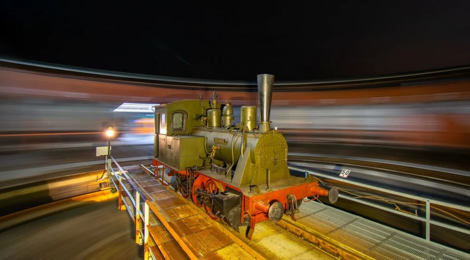 Farbfotografie einer sich auf einer Drehscheibe befindenden historischen Lokomotive