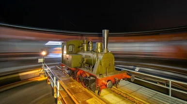 Farbfotografie einer sich auf einer Drehscheibe befindenden historischen Lokomotive